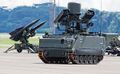 عرض توضيحي لـ M-113A2 Ultra Mechanized Igla IFU، يظهر في الخلفية قاذفة I-HAWK SAM.